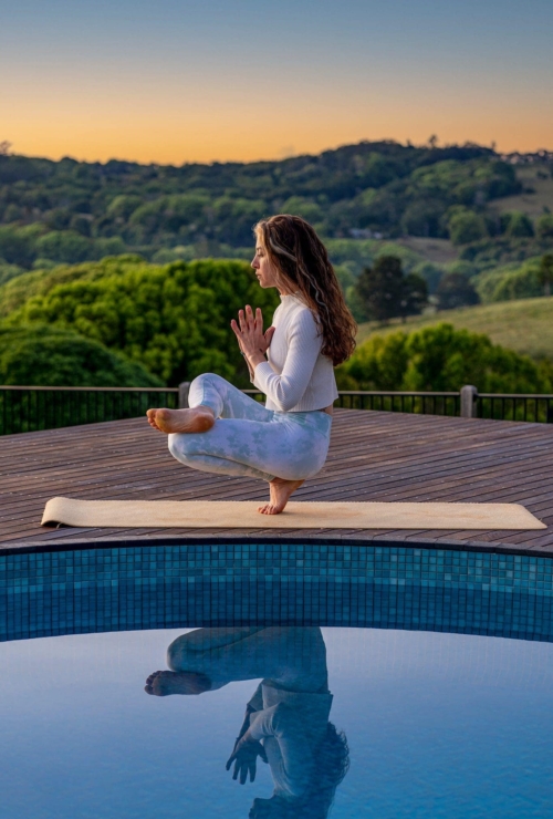 yoga teacher in a meditation pose by the heartwood farm cottage swimming pool n the morning light