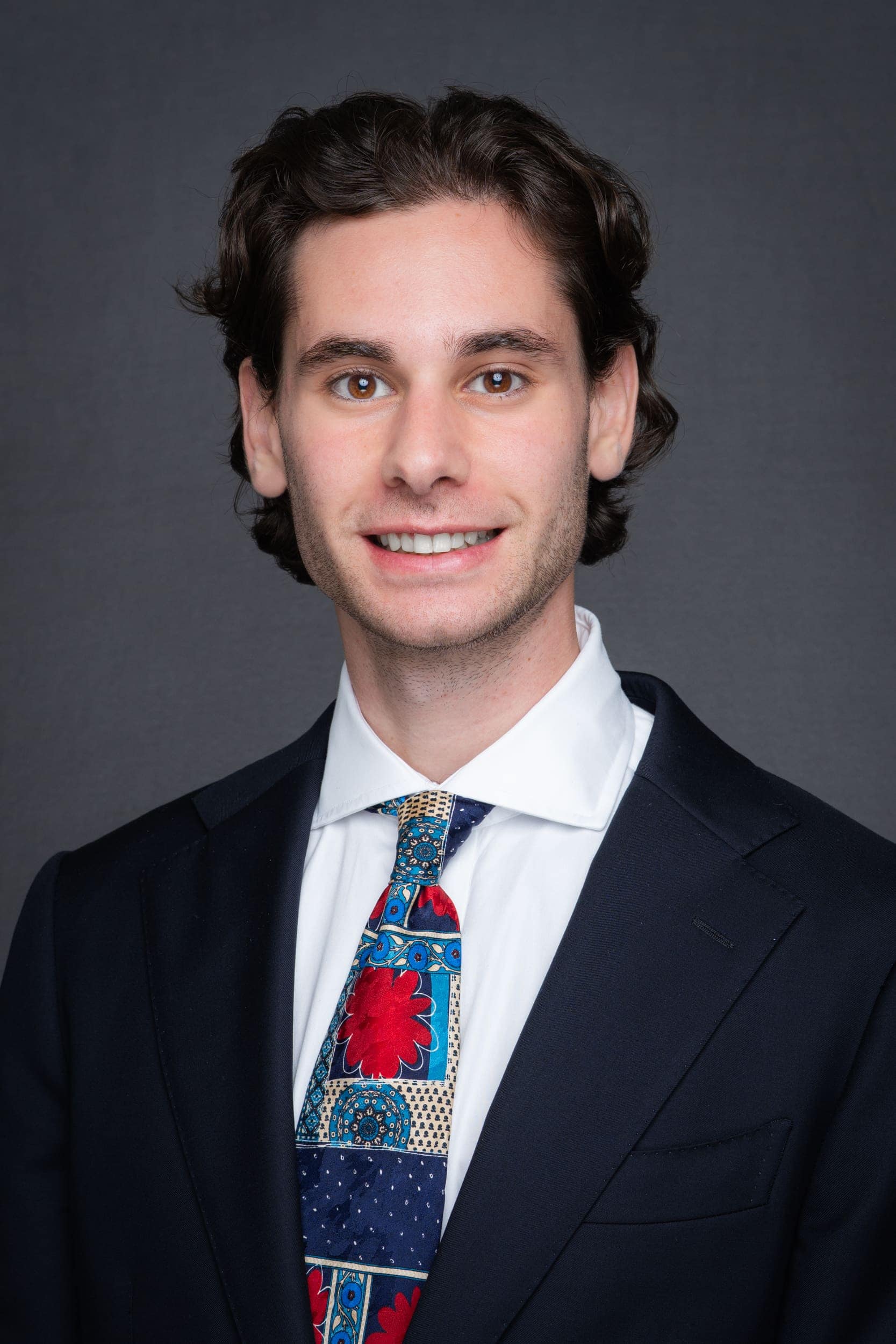 Mobile-Studio-Headshot-Sydney-NSW Young dark haired man wearing a colourful tie having his headshot taken with a mobile studio headshot set-up in Sydney NSW