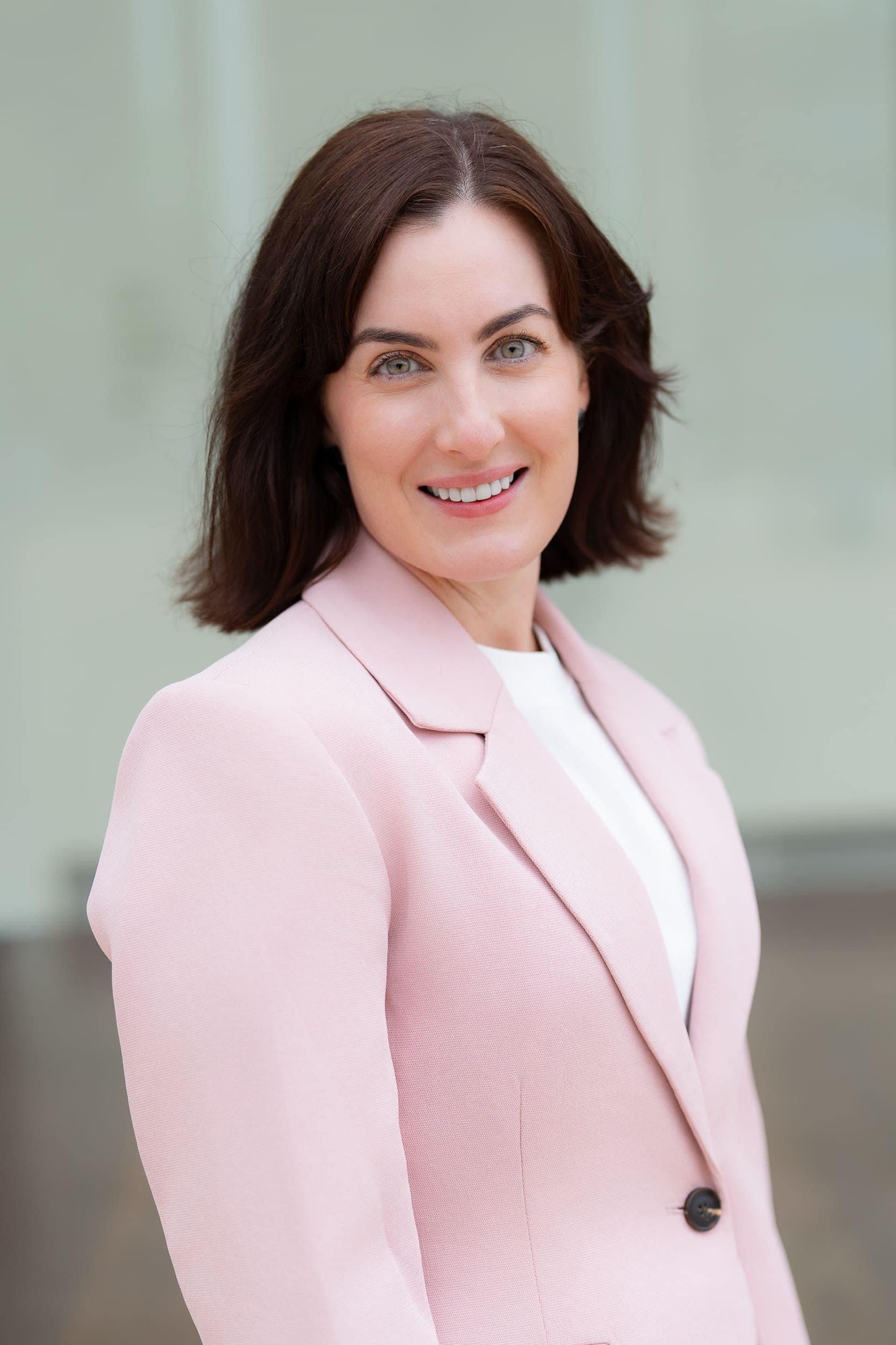 Job-Seeker-Headshot-Sydney-NSW Young dark haired woman wearing a pink jacket having her headshot taken by professional Sydney photographer Georgie Greene