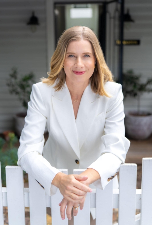 Woman in a white jacket leaning over a white fence having her personal branding taken by Sydney personal branding photographer Georgie Greene