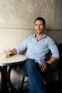 Sydney-Dating-Photographer-NSW – Professional Photographer Sydney Dark hair man with beard wearing a light blue shirt sitting at a pub table having his dating photo taken by top Sydney dating photographer Georgie Greene