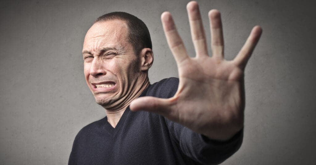 Hate-Having-Photo-Taken-Sydney-NSW – Professional Photographer Sydney Man holding his hand up with a discussed expression on his face as he hates having his photo taken
