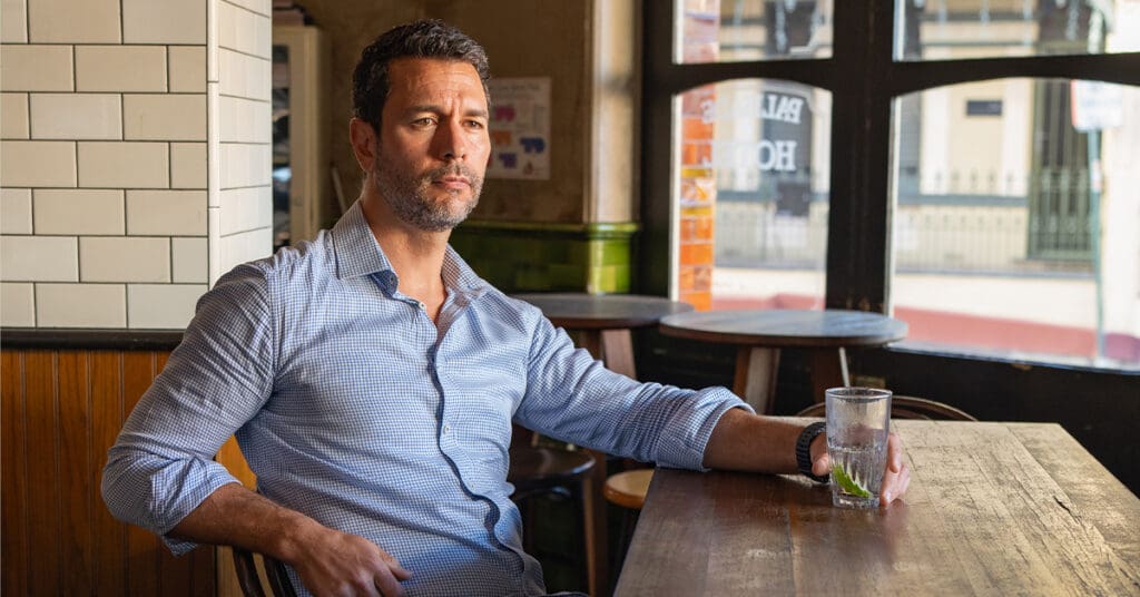 Sydney-dating-photography-feature-page – Professional Photographer Sydney Man in a blue shirt sitting in a pub having his dating photo taken by top Sydney dating photographer Georgie Greene