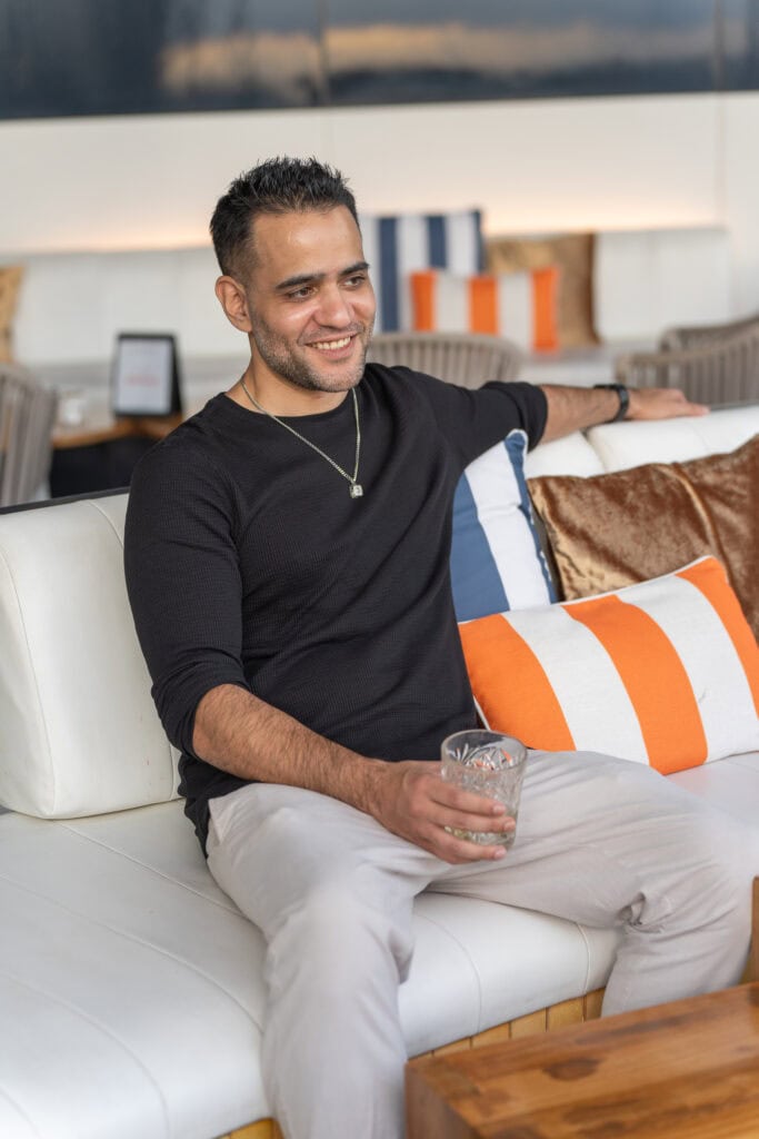 Smiling indian man with a drink in a cocktail bar having his dating photos taken by Sydney dating photographer Georgie Greene