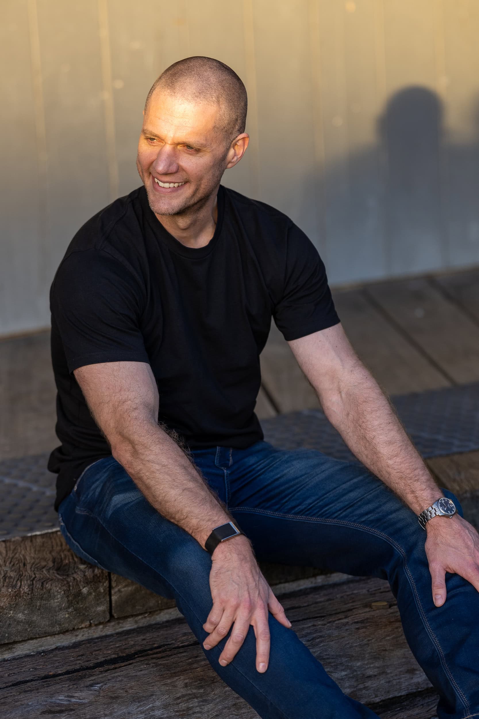 bald man sitting down and smiling and have a candid dating shot taken