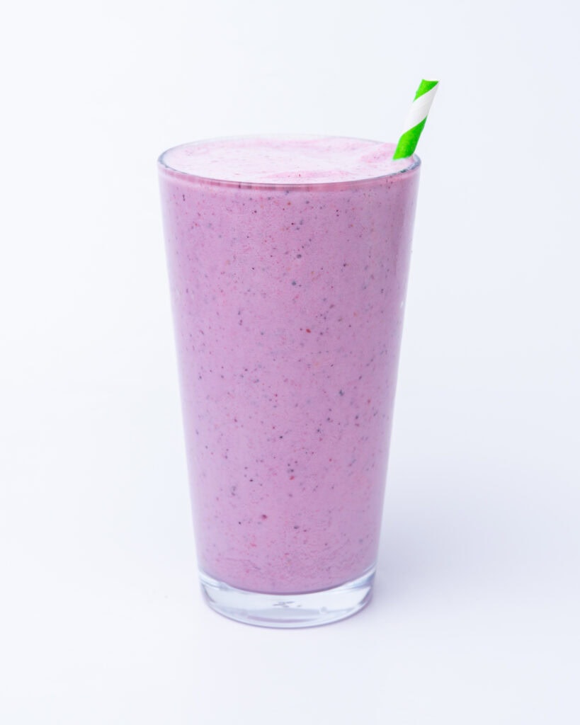 Berry smoothie with a straw in a long glass
