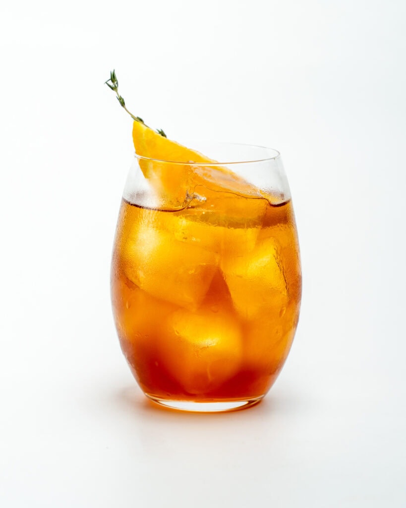 aperol spritz with a leave of thyme and orange in an iced glass