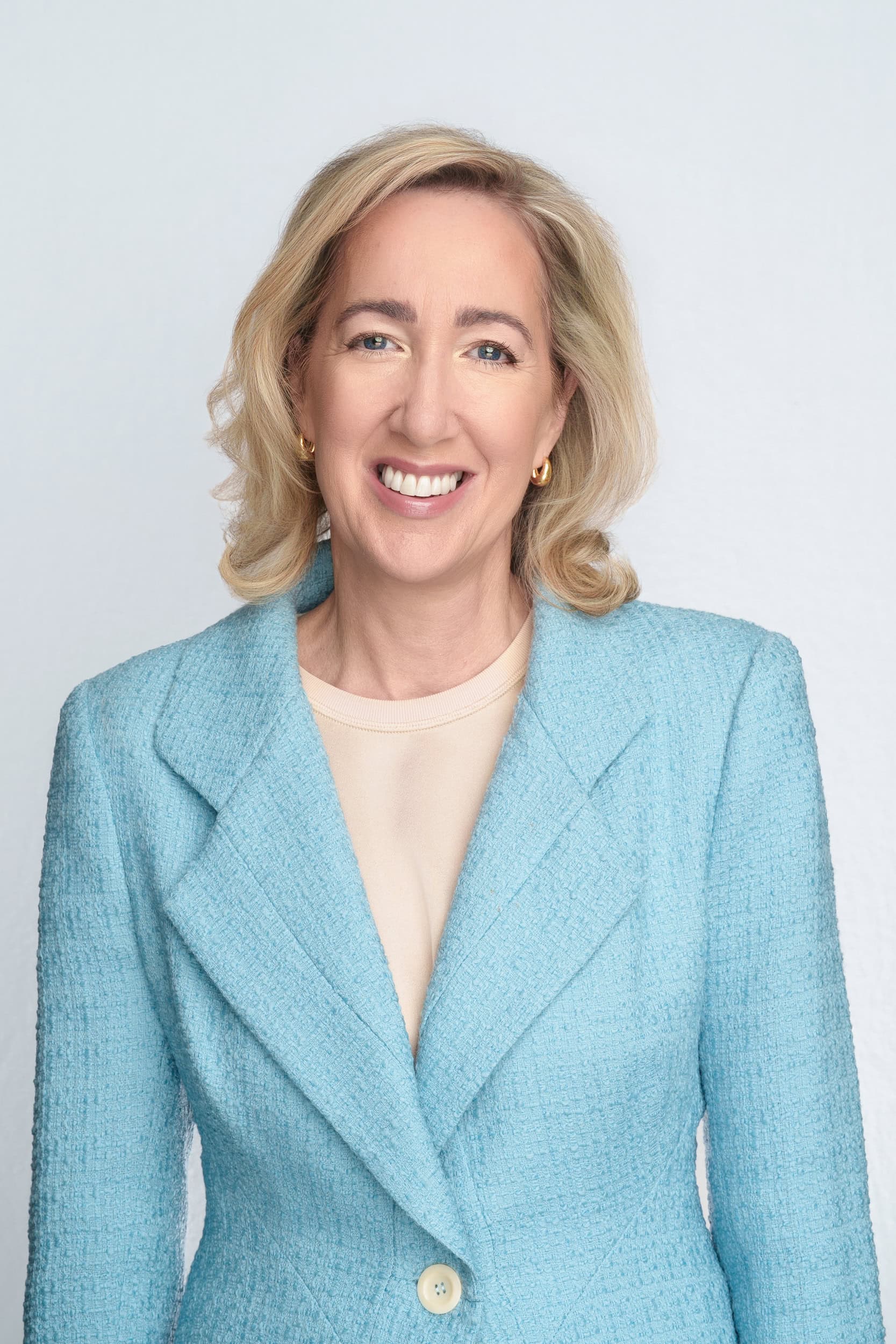 blonde woman wearing a eggshell blue woollen jacket while having a professional headshot taken