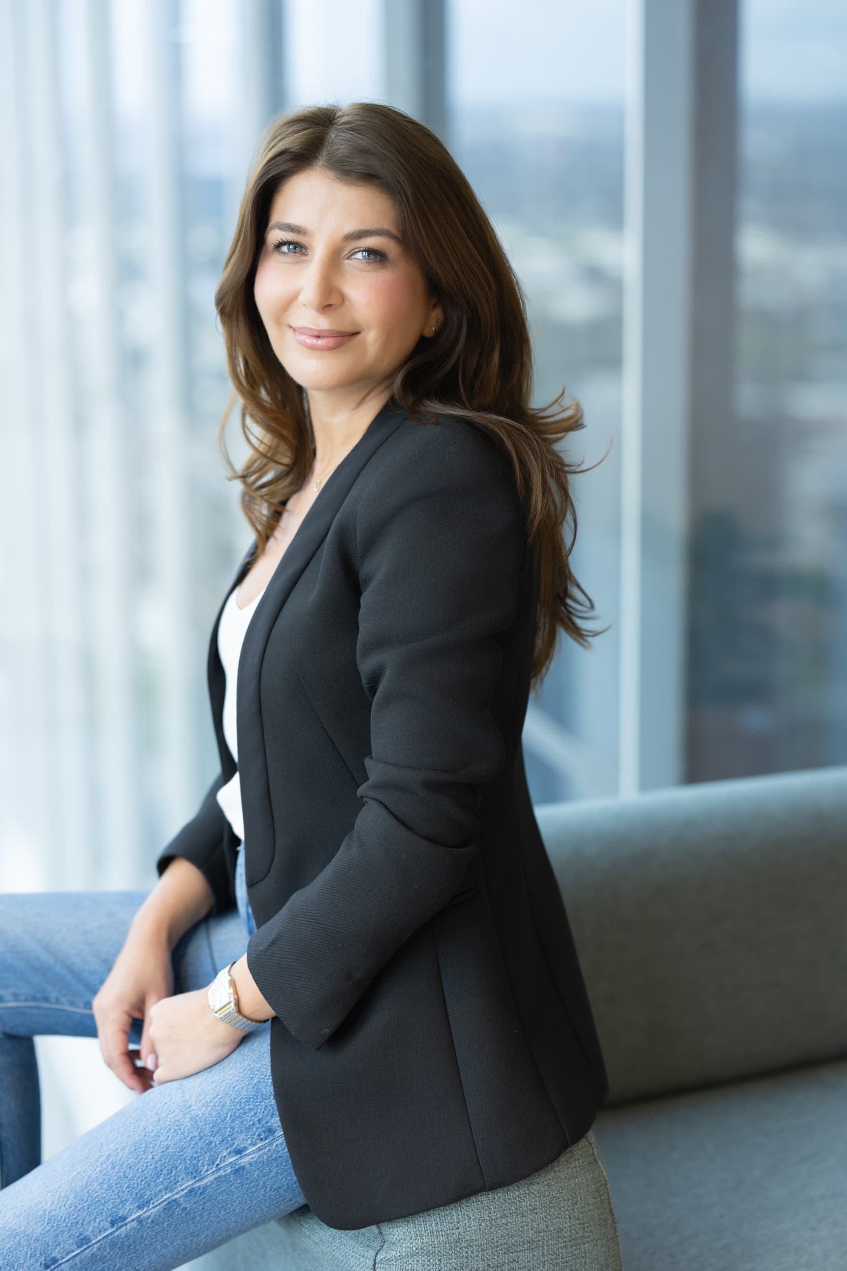 dark haired lawyer sitting on a sofa arm having her branding portrait taken by personal branding photographer Georgie Greene